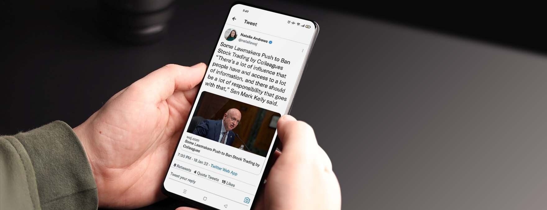 A man is holding a mobile phone in which the tweet of Natelle Andrews is displayed