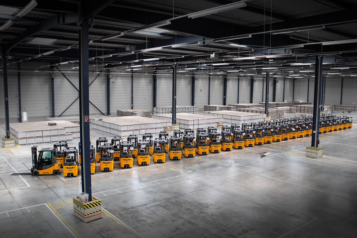 A large number of forklifts are parked in the Jungherinrich' warehouse in this photo.