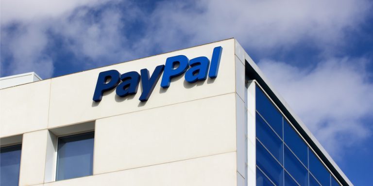 The Paypal logo is displayed on a white structure with blue mirrors building.