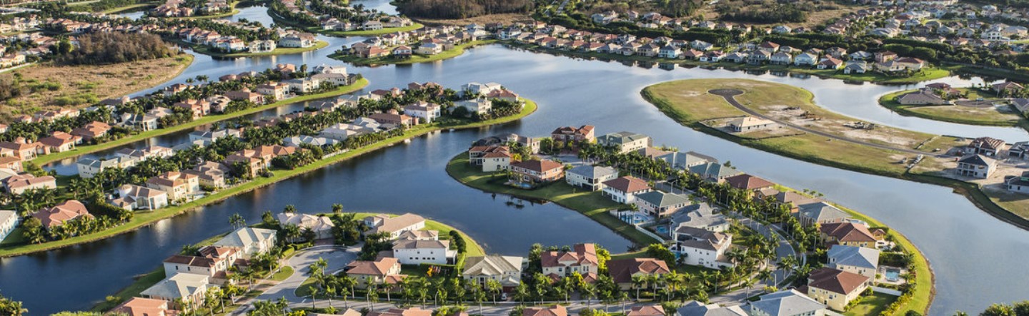 Beautiful villas with tiled rooftops and palm trees to the sides are arranged around a scenic lake in Florida, USA