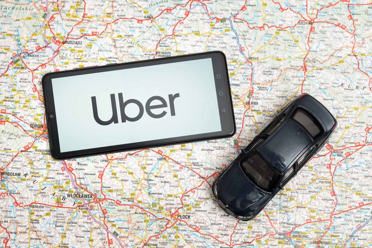 A smartphone with the Uber logo and a car displayed on a map.