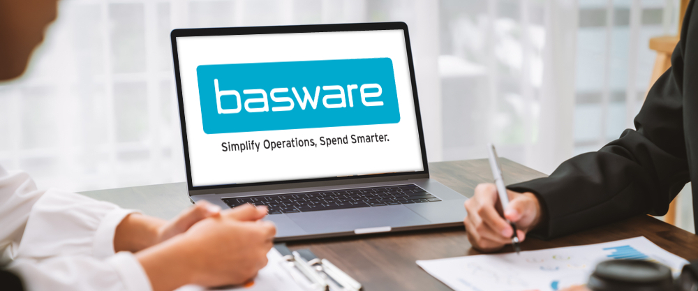 There is a laptop on a table on which Basware's logo is displayed and two people are calculating the finances.