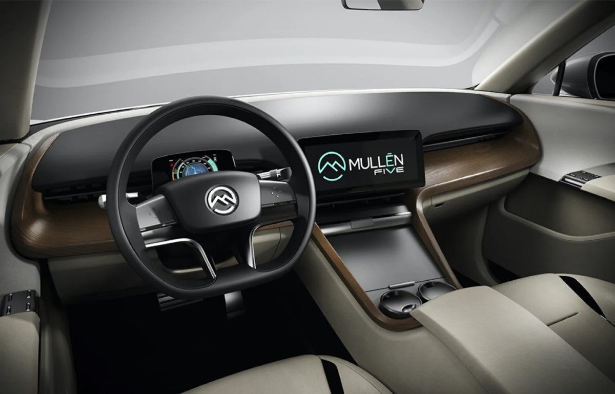  The image depicts an inside view of the car, including the steering wheel and an LED with the Mullen Automotive Inc emblem.