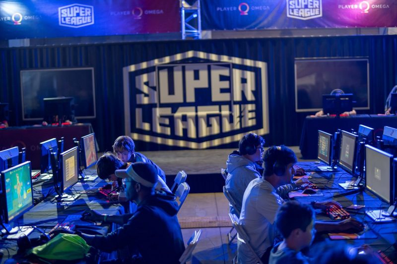 Many people are seated in front of their computers at desks in a hall of Super League Gaming Inc.